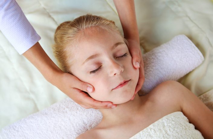 Masseur doing face massage to child.